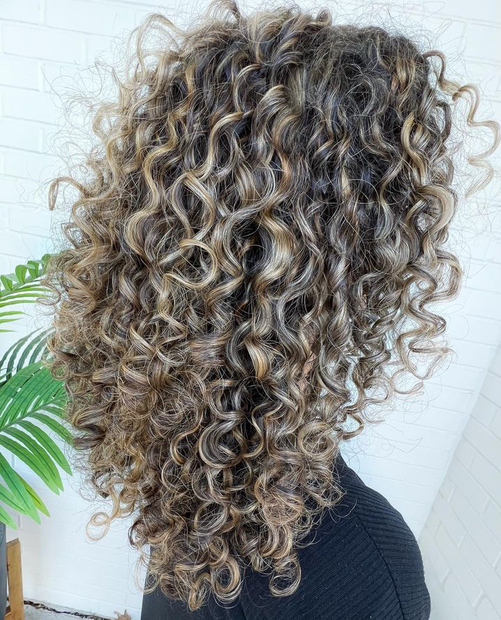 a very dimensional curly head of hair with a subtle round shape. styled with curly hair products